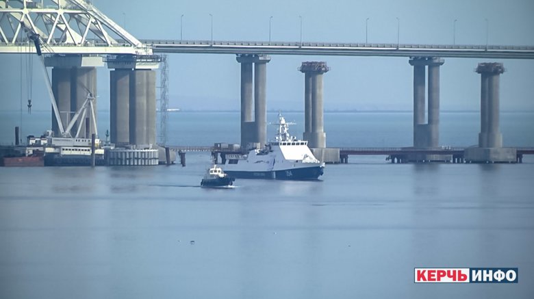 Под аркой Крымского моста, кроме неизвестного корабля, находятся три российских военных катера и над мостом кружат два военных вертолета.