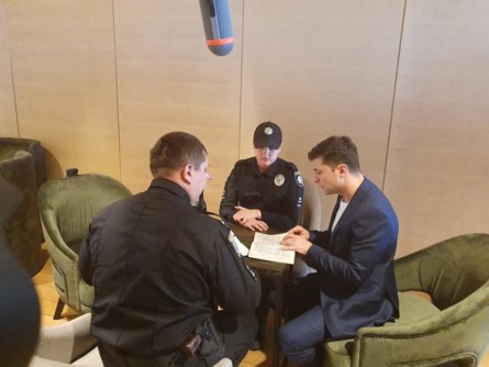 Правоохранители вручают кандидату на пост президента Украины Владимиру Зеленскому протокол об административном нарушении за то, что он показал заполненный избирательный бюллетень.